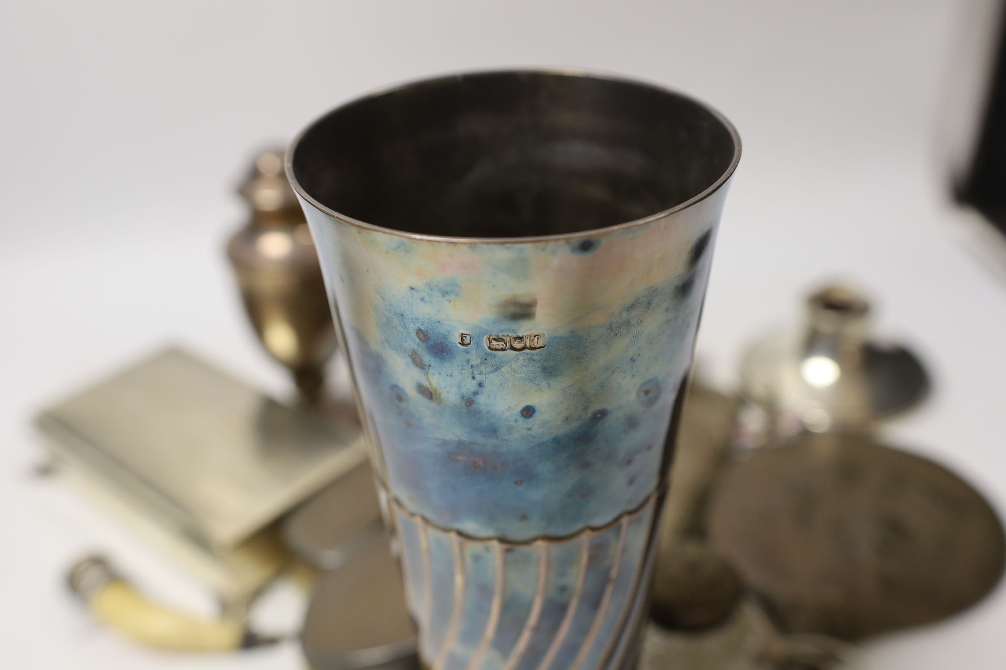 A group of sundry silver including an Edwardian demi-wrythened vase, London, 1901, 24.3cm, mounted hand mirror and three brushes, cigarette box, sugar caster and a damaged inkwell, together with a 1970's silver and ename